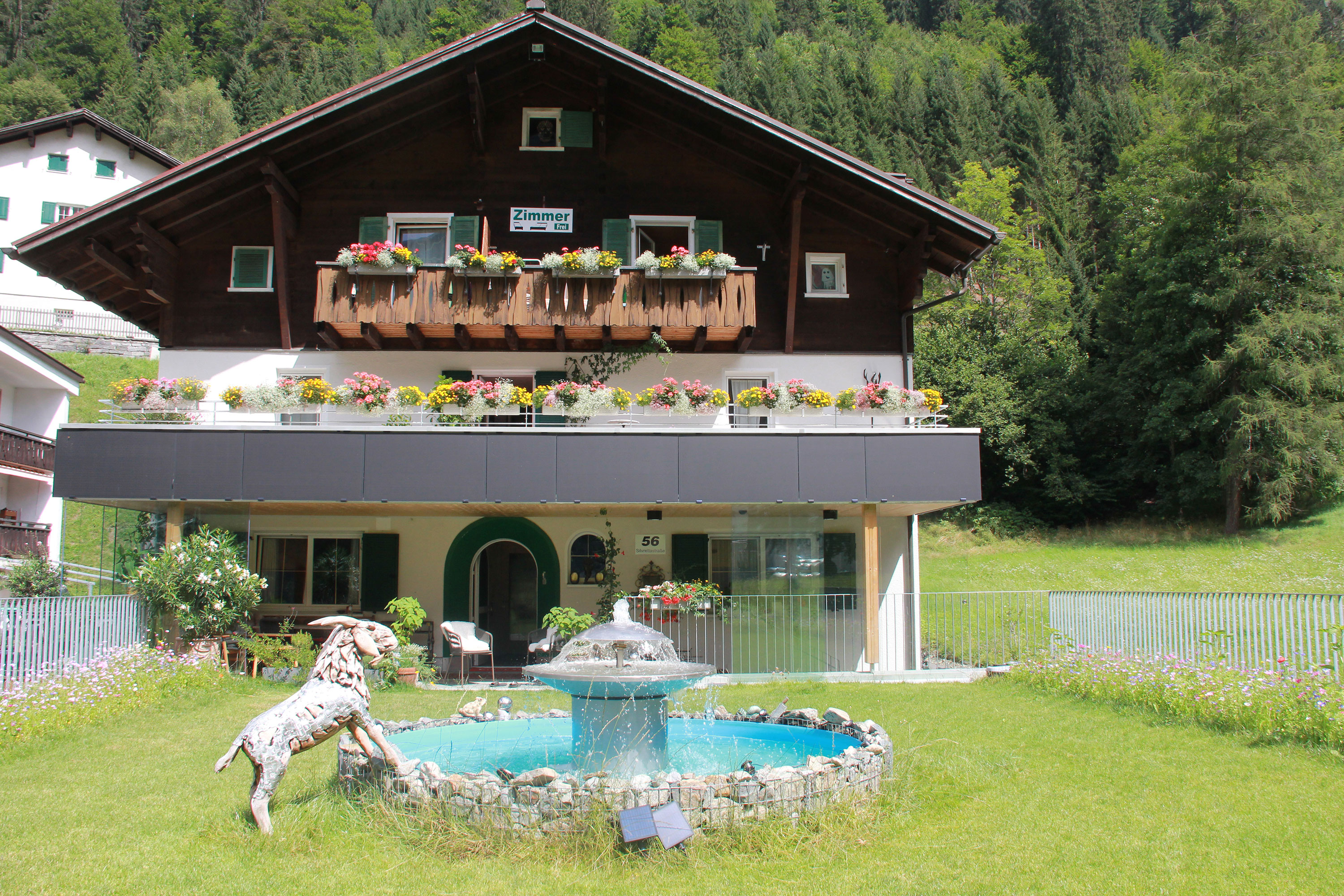 Hausansicht mit einem Brunnen im Garten